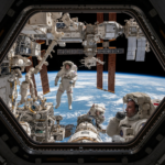 The International Space Station orbiting Earth with solar panels reflecting the sun and the blue curve of the planet visible below.