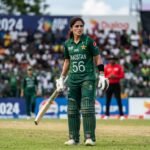A wide shot of a cricket stadium where a Pakistan woman cricketer is being spoken to by an official during a match against India.
