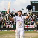 Joe Root raises his bat in celebration after reaching a historic milestone in a Test match against Pakistan.