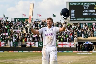 Joe Root raises his bat in celebration after reaching a historic milestone in a Test match against Pakistan.