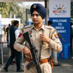 A Delhi Police officer in uniform holding a firearm, symbolizing the security breach and subsequent inquiry.