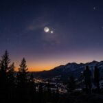 A brilliant white Venus shining brightly next to a thin, glowing crescent moon in a dark twilight sky.