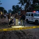 Forensic investigators at a crime scene in India with police barricades and emergency lights.