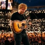 A close-up emotional shot of Ed Sheeran performing on stage with his guitar during the Mathematics Tour.