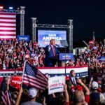 Former President Donald Trump speaking at a Save America rally in Ohio, gesturing toward a cheering crowd under bright lights.