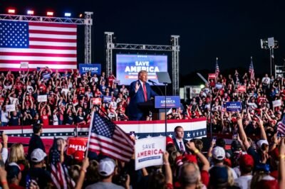 Former President Donald Trump speaking at a Save America rally in Ohio, gesturing toward a cheering crowd under bright lights.