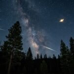 A breathtaking photograph of the night sky showing the golden planet Saturn glowing brightly while a vivid Orionid meteor streaks through the atmosphere nearby.