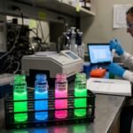 Microscopic view of fluorescent nanoparticles glowing in a dark laboratory setting, illustrating advanced chemical engineering and molecular diagnostics.