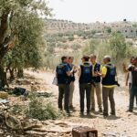 Diplomatic personnel and local officials in a tense confrontation in a West Bank olive grove during the harvest season.