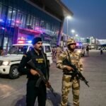 Indian security forces and Gujarat ATS officers standing guard at Ahmedabad airport terminal during a counter-terrorism operation.