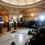 International flags of Ireland, Norway, Spain, and Palestine displayed at a formal government press conference.
