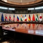 An empty G20 conference hall with international flags, symbolizing the diplomatic rift and the absence of a group photo.
