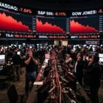 A digital stock market ticker display showing massive red percentage drops for major technology companies on a trading floor.